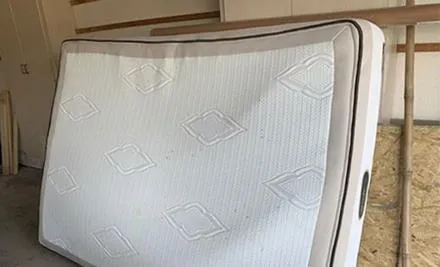 Mattress removal crew carrying an old mattress out of a Gainesville FL apartment